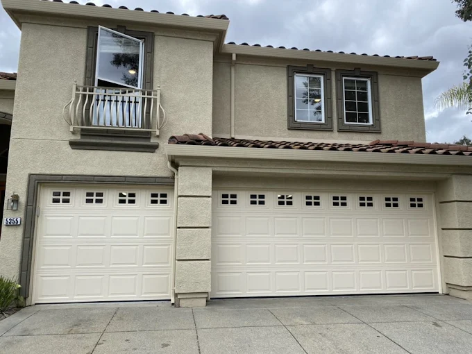 Two cream-colored carriage-style garage doors on a stucco home